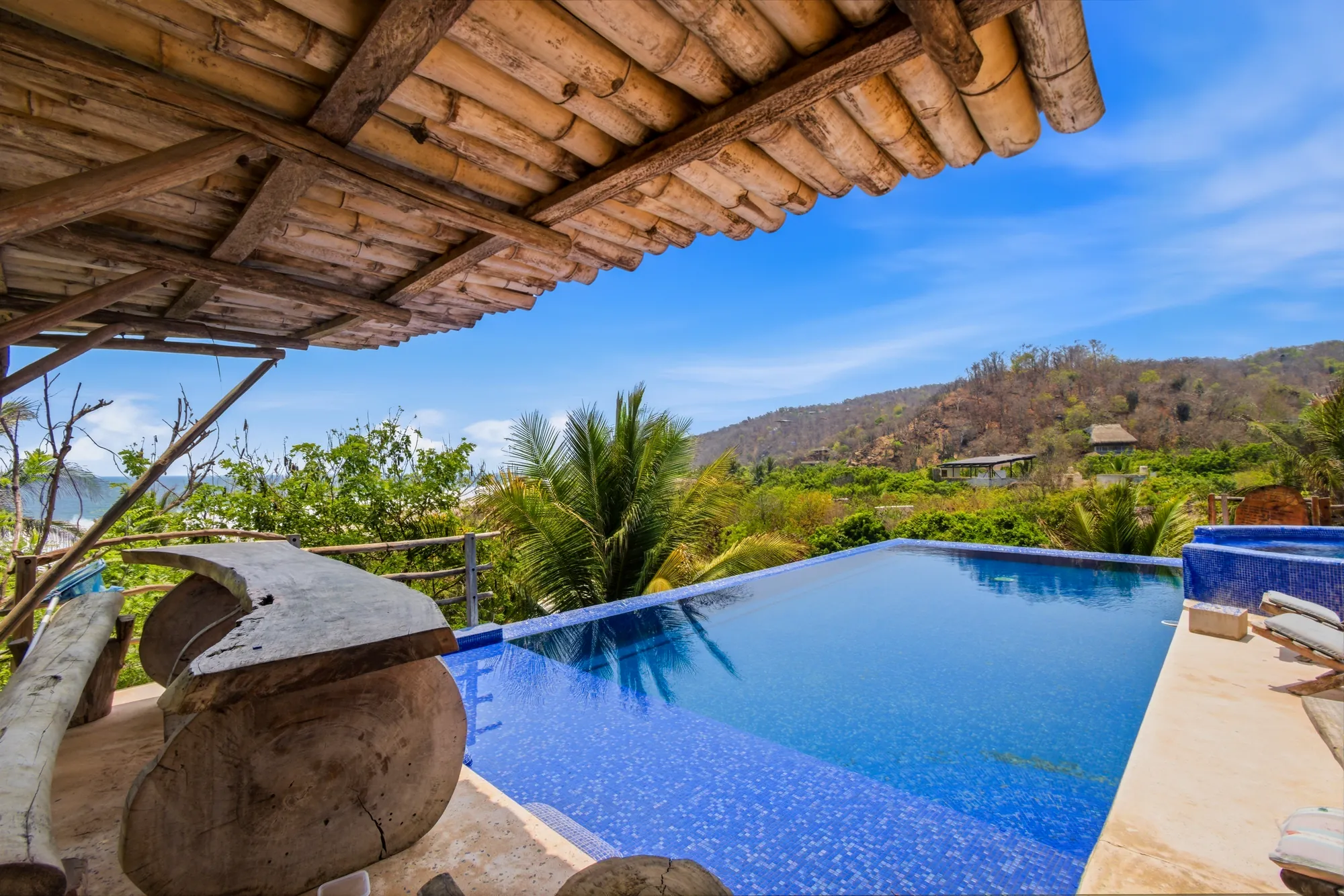 Infinity pool under a bamboo palapa with jungle and ocean views