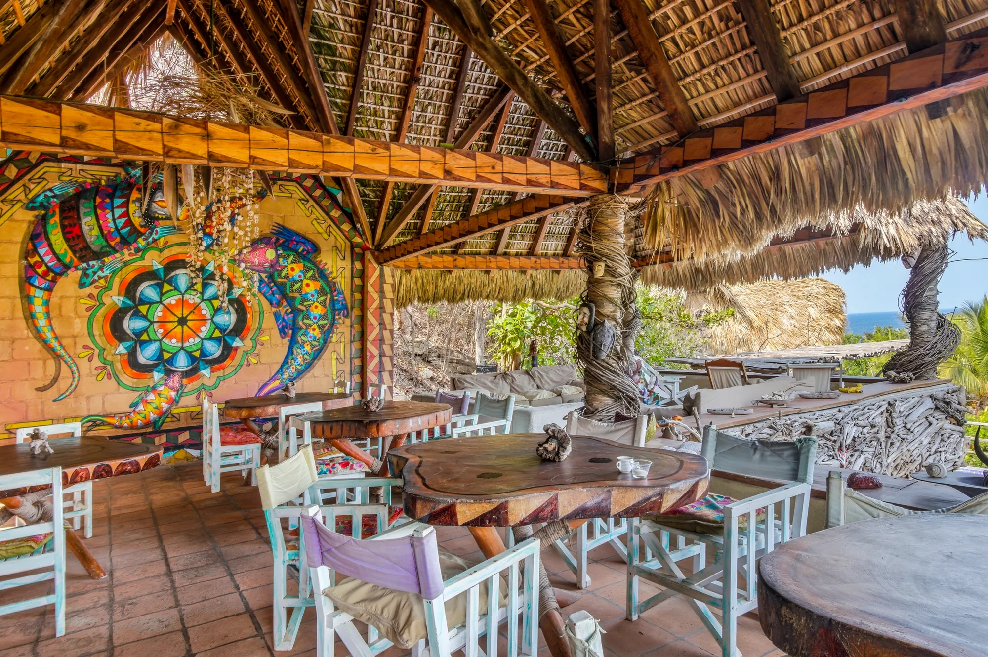 Colorful hand-painted mural and wooden tables at our Mazunte restaurant